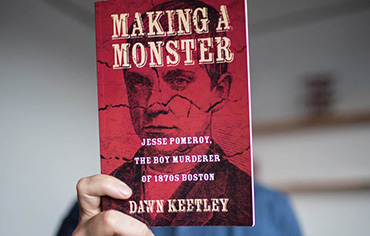 Photo of a person holding up book "Making a Monster" in front of their face