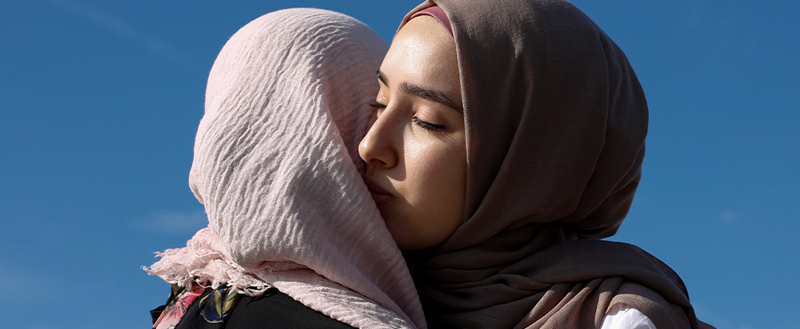 Two women in hijabs hugging each other